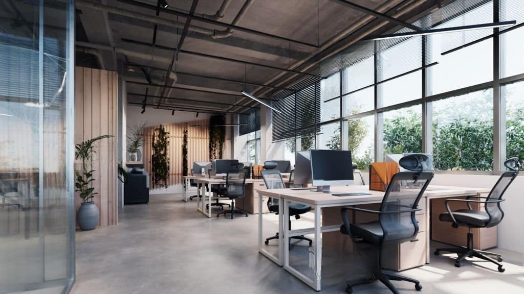 Stock photograph shows a contemporary office space including an exposed concrete floor and a large number of plants