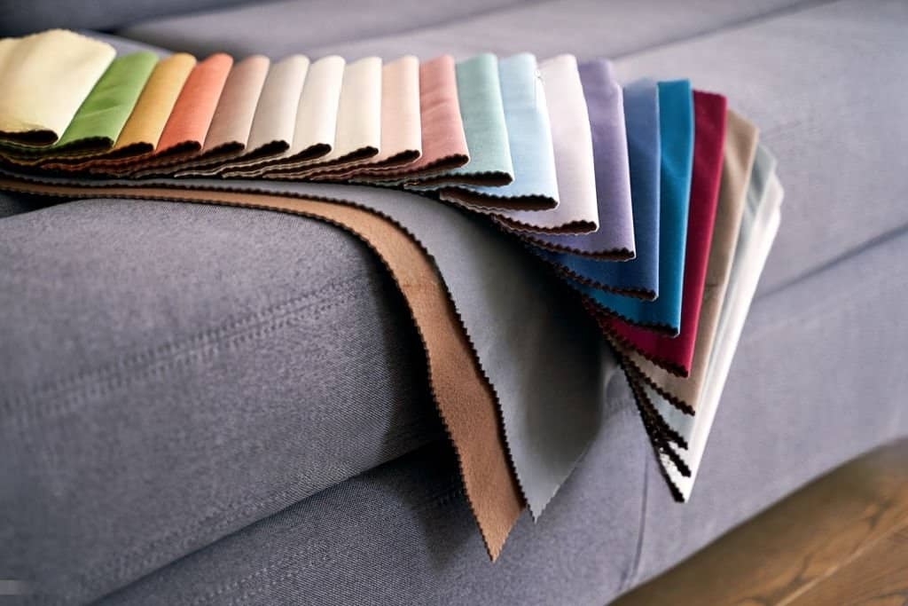 Stock photograph featuring swatches of vibrant upholstery fabric arranged on a domestic couch